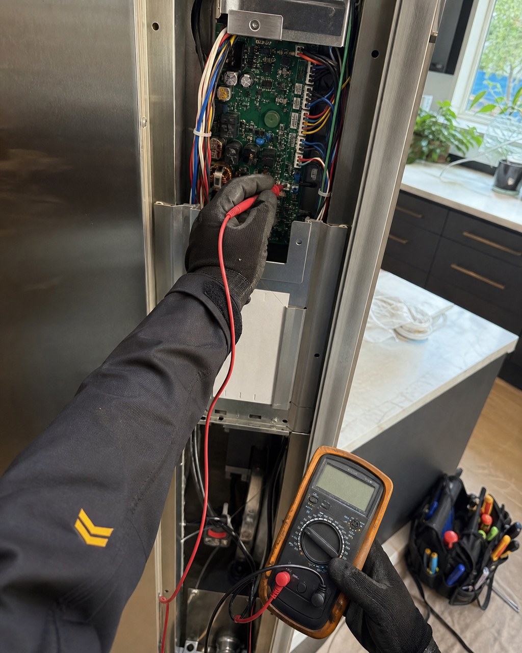 Sub-Zero Fremont technician probing a built-in refrigerator control board with a multimeter